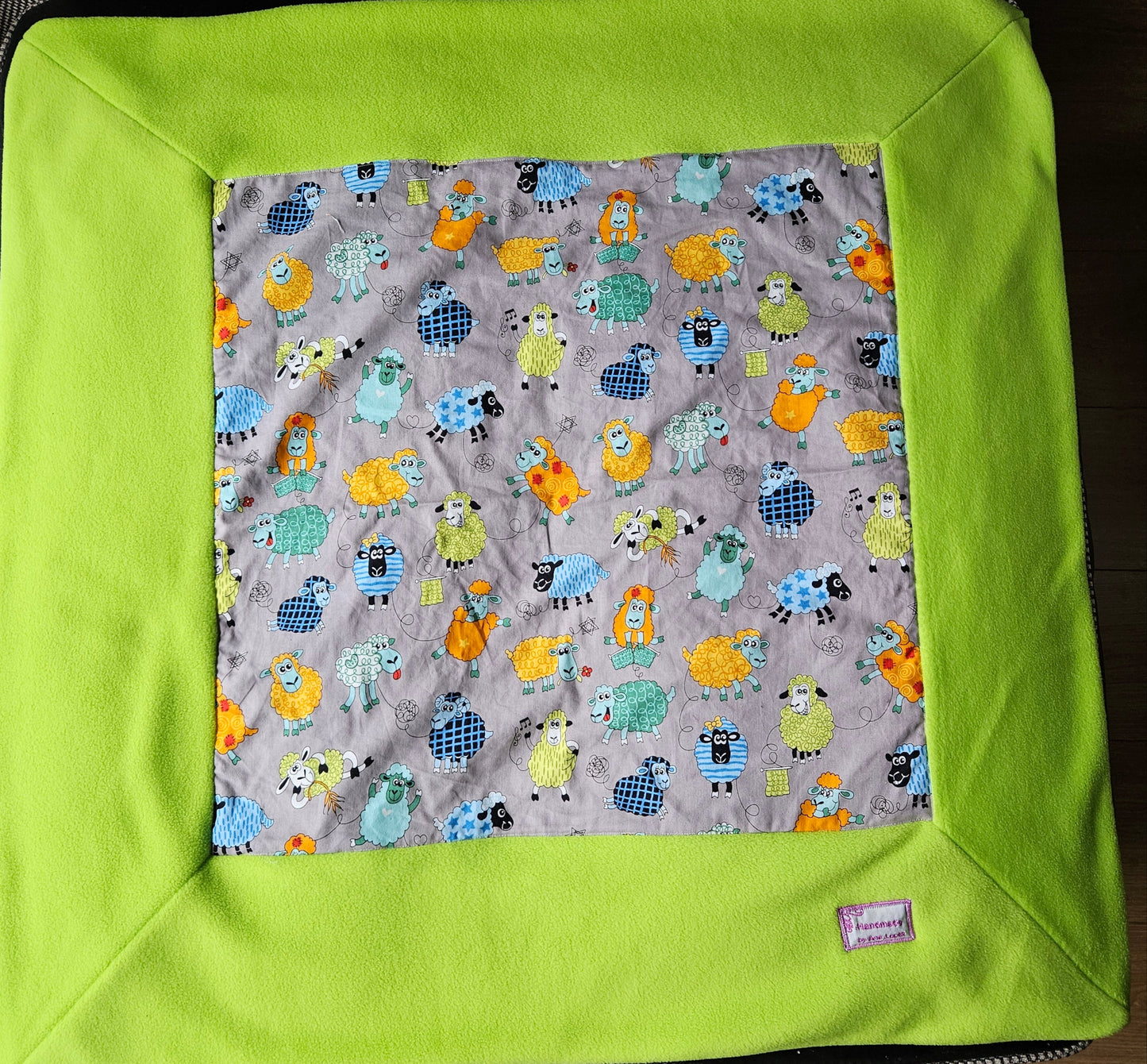 Fun Colourful Sheep's Handmade Blanket on Grey background. Double sided, cotton fabric in one side, and bright fluorescent green fleece at the back.