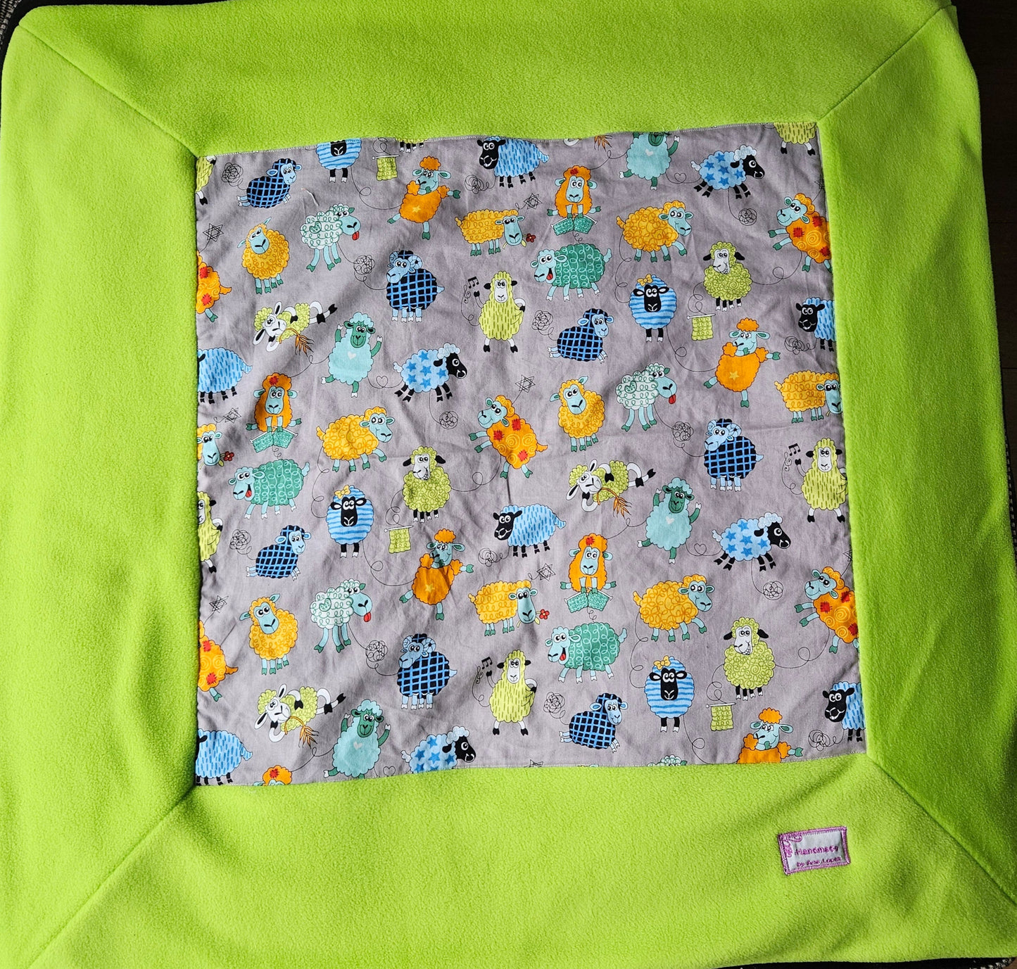 Fun Colourful Sheep's Handmade Blanket on Grey background. Double sided, cotton fabric in one side, and bright fluorescent green fleece at the back.