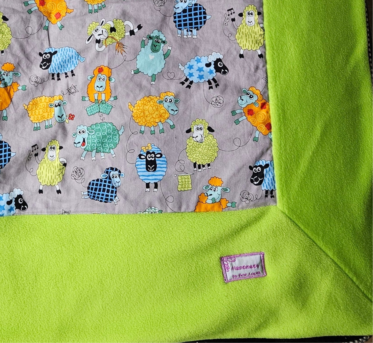 Fun Colourful Sheep's Handmade Blanket on Grey background. Double sided, cotton fabric in one side, and bright fluorescent green fleece at the back.