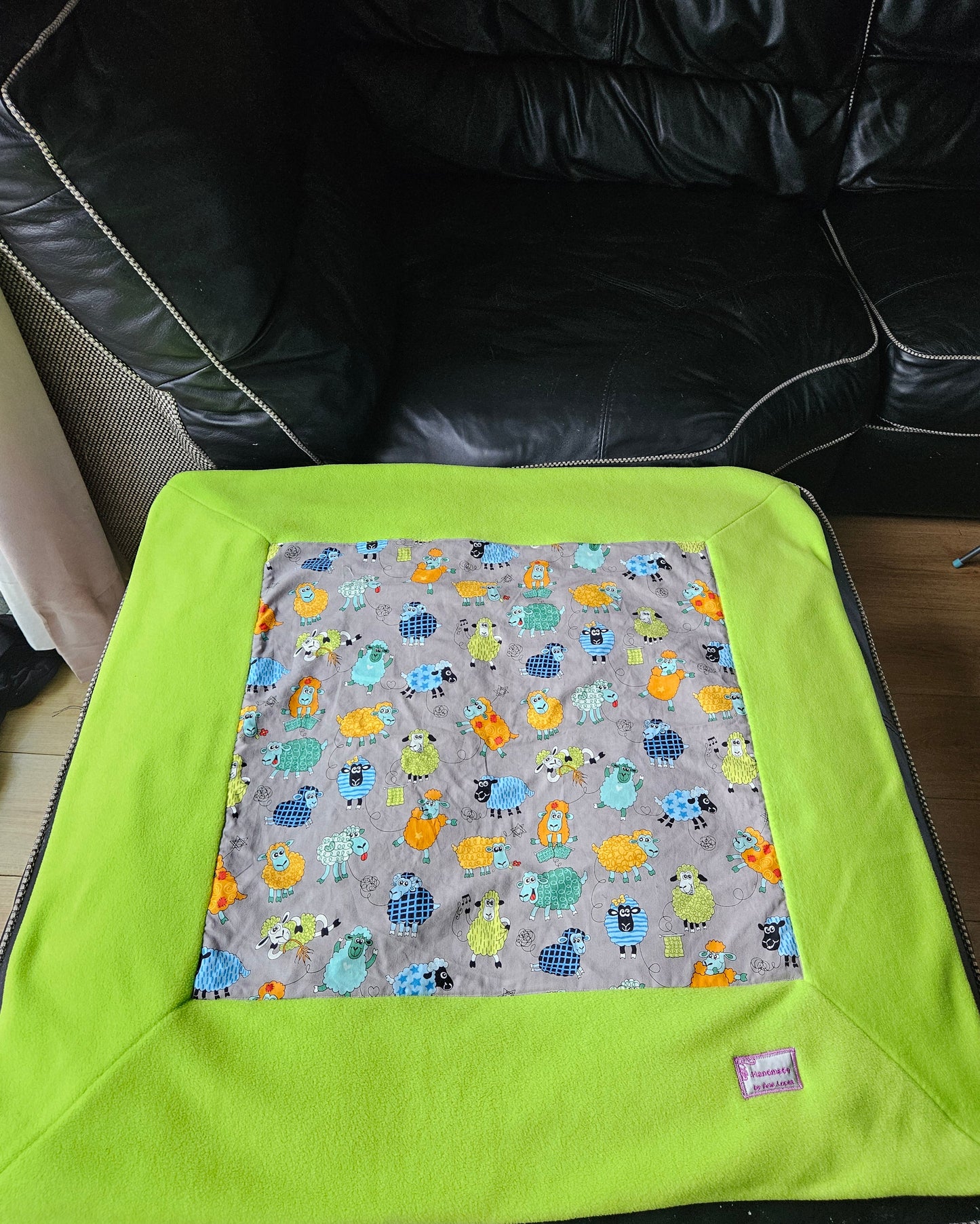 Fun Colourful Sheep's Handmade Blanket on Grey background. Double sided, cotton fabric in one side, and bright fluorescent green fleece at the back.