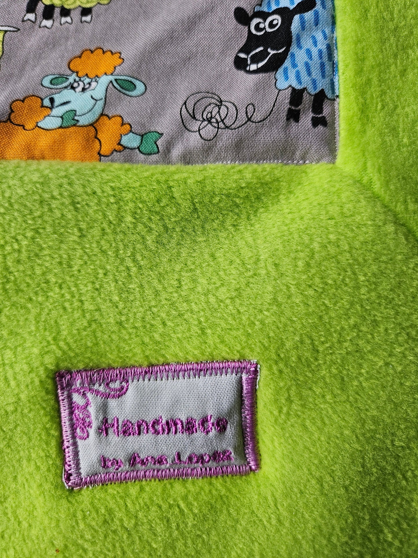 Fun Colourful Sheep's Handmade Blanket on Grey background. Double sided, cotton fabric in one side, and bright fluorescent green fleece at the back.