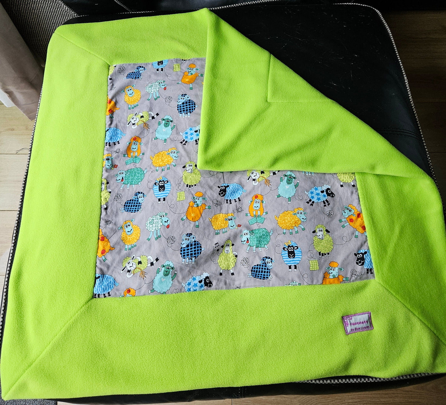 Fun Colourful Sheep's Handmade Blanket on Grey background. Double sided, cotton fabric in one side, and bright fluorescent green fleece at the back.