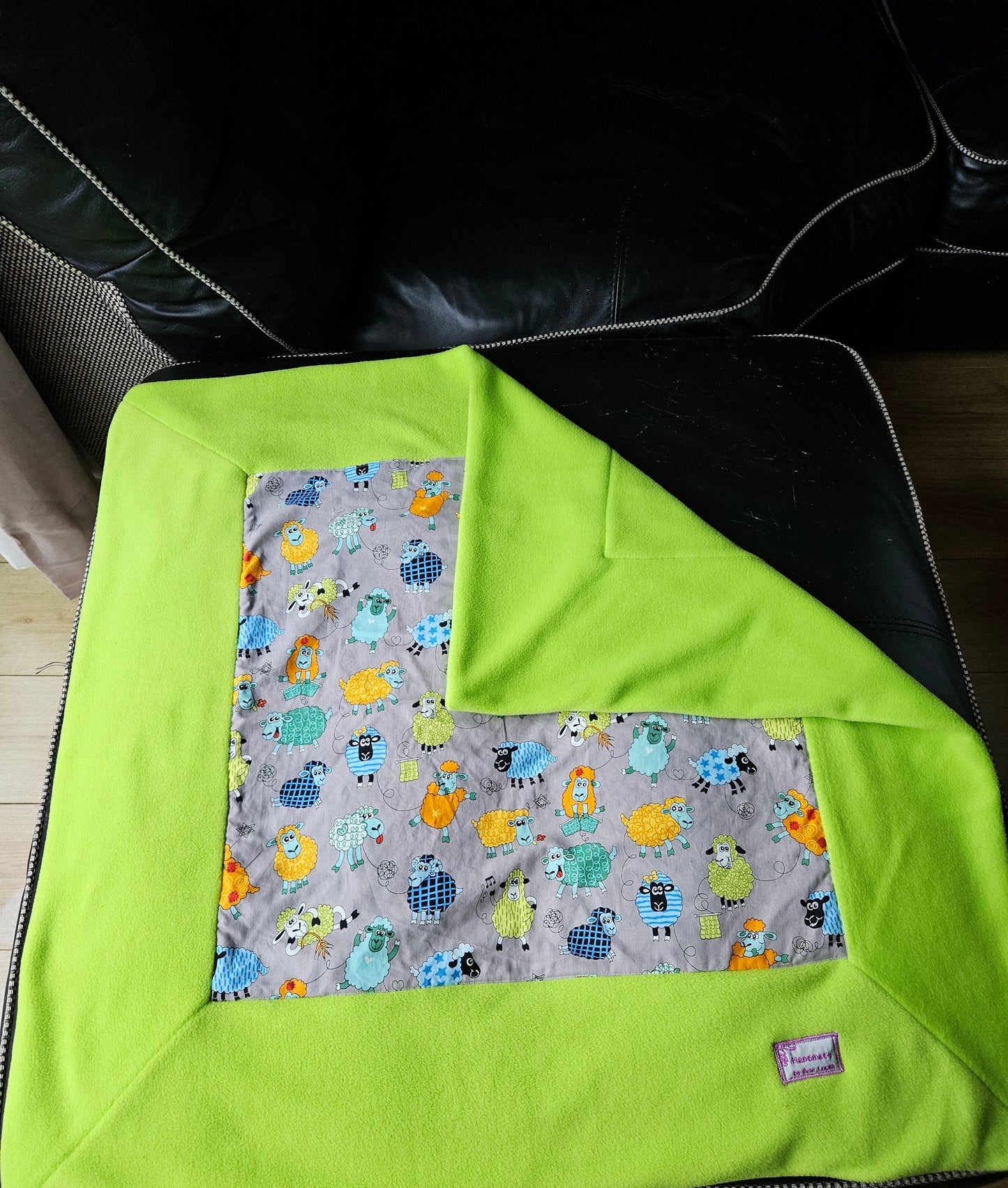 Fun Colourful Sheep's Handmade Blanket on Grey background. Double sided, cotton fabric in one side, and bright fluorescent green fleece at the back.