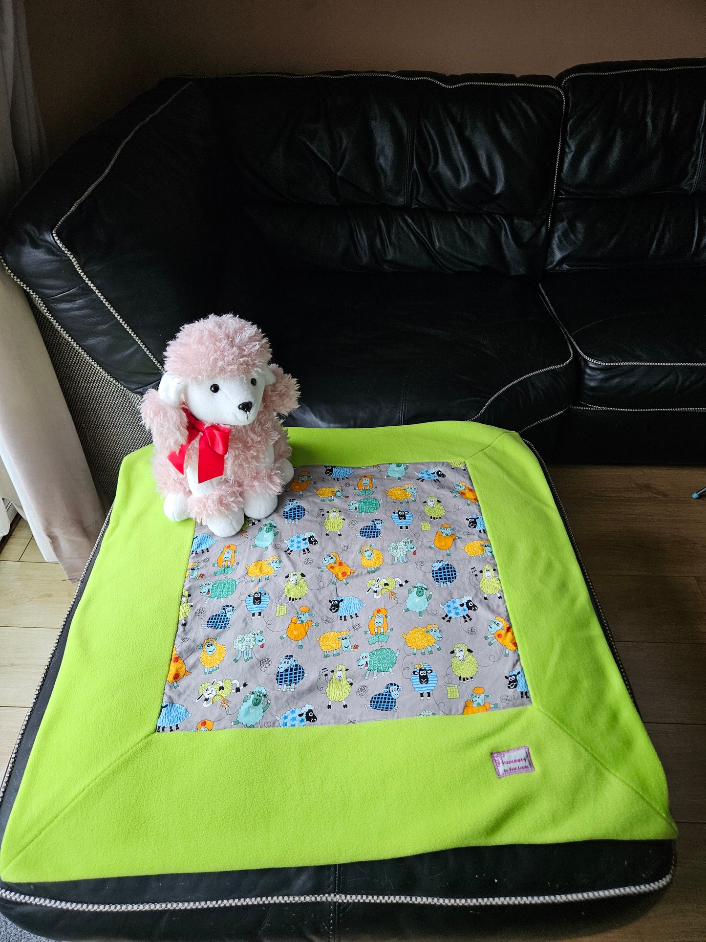 Fun Colourful Sheep's Handmade Blanket on Grey background. Double sided, cotton fabric in one side, and bright fluorescent green fleece at the back.