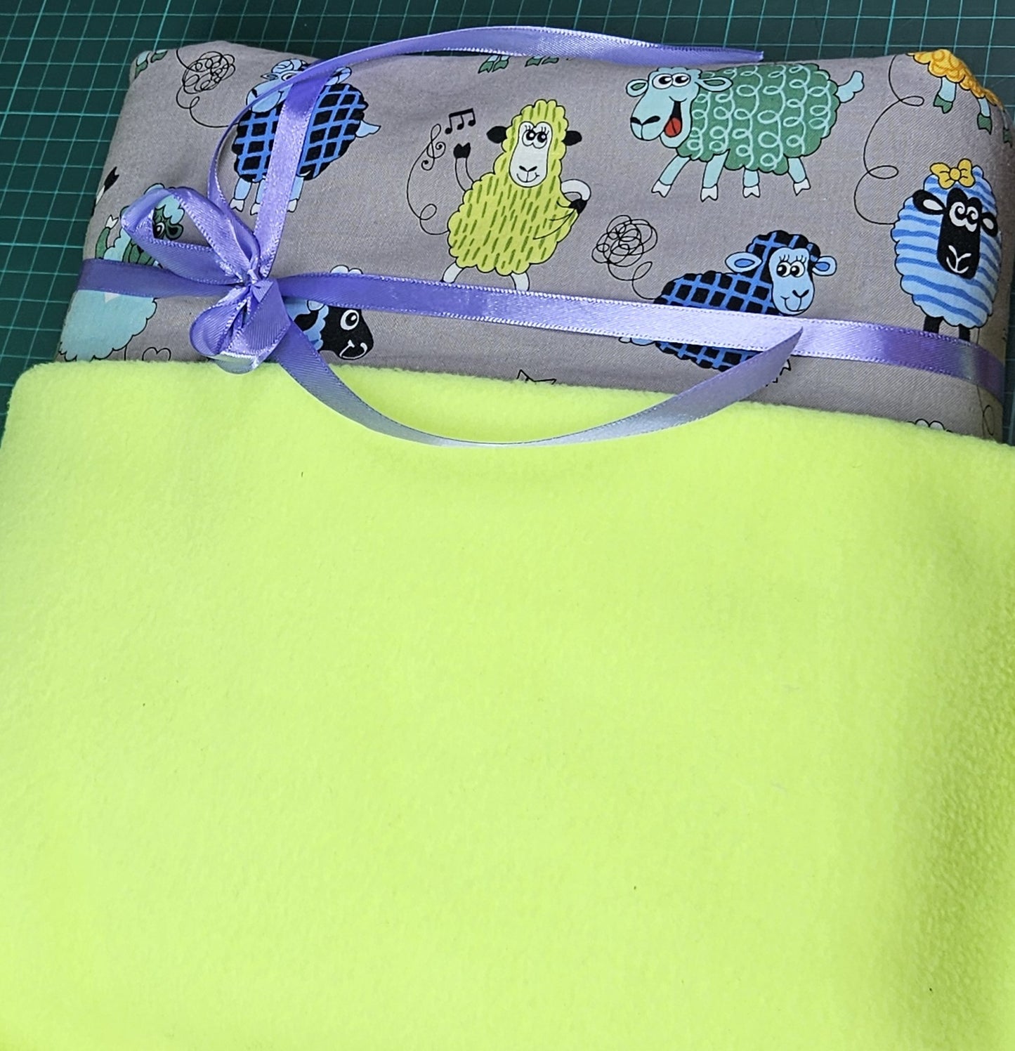 Fun Colourful Sheep's Handmade Blanket on Grey background. Double sided, cotton fabric in one side, and bright fluorescent green fleece at the back.